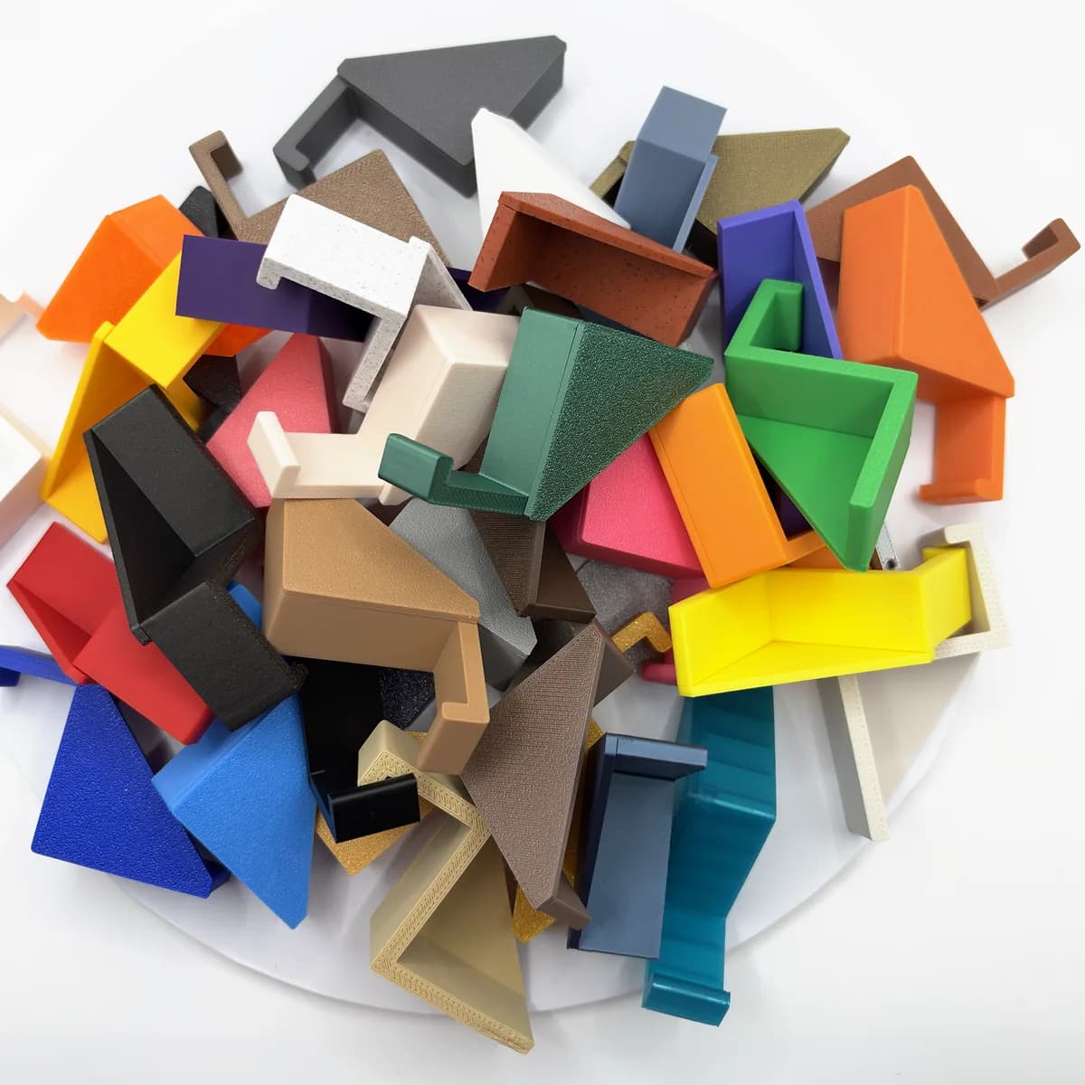 A pile of Headphone Hangers in about thirty single colours on a white disc, seen from above