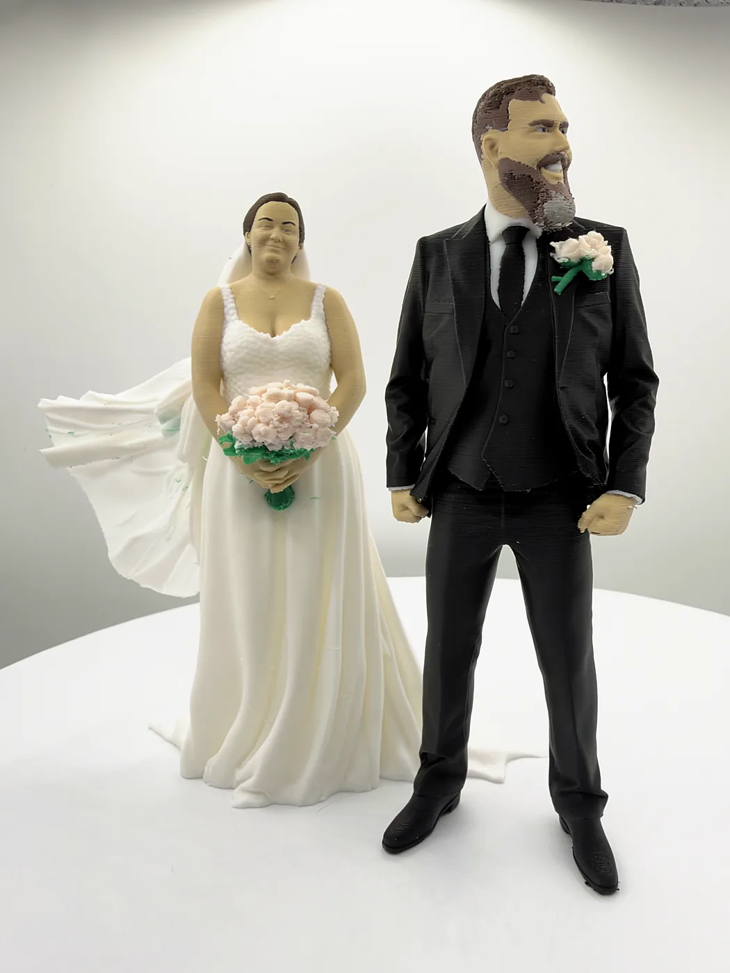 The bride and groom cake topper figures side by side, her veil blowing out behind her